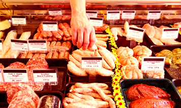 hand reaching into display case of meat