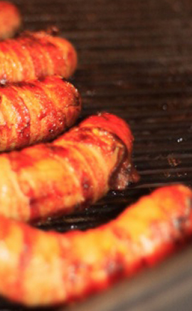 sausages wrapped in bacon on BBQ